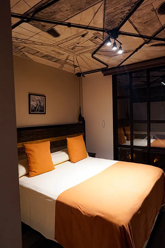 Cama matrimonial con respaldo de madera y ventana interior de hierro