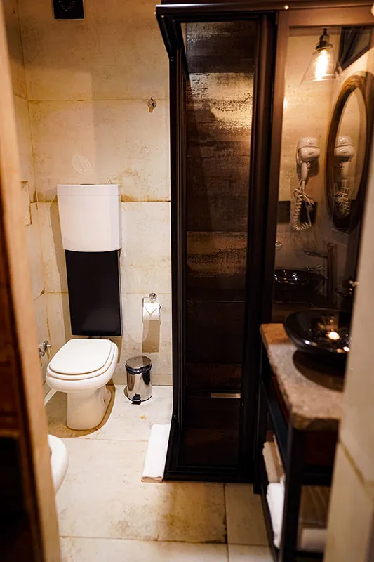Baño privado con ducha, bacha negra y mesada de piedra