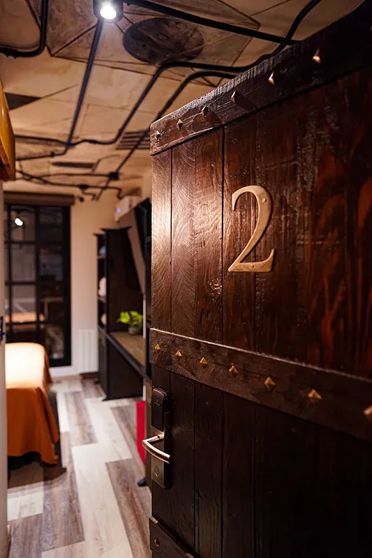 Puerta de madera maciza con tachas y número de bronce de la habitación