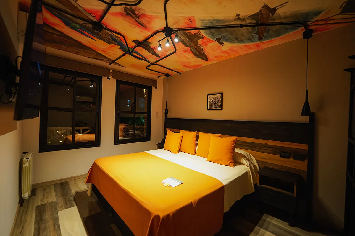 Cama matrimonial bajo el mural de barcos voladores del techo