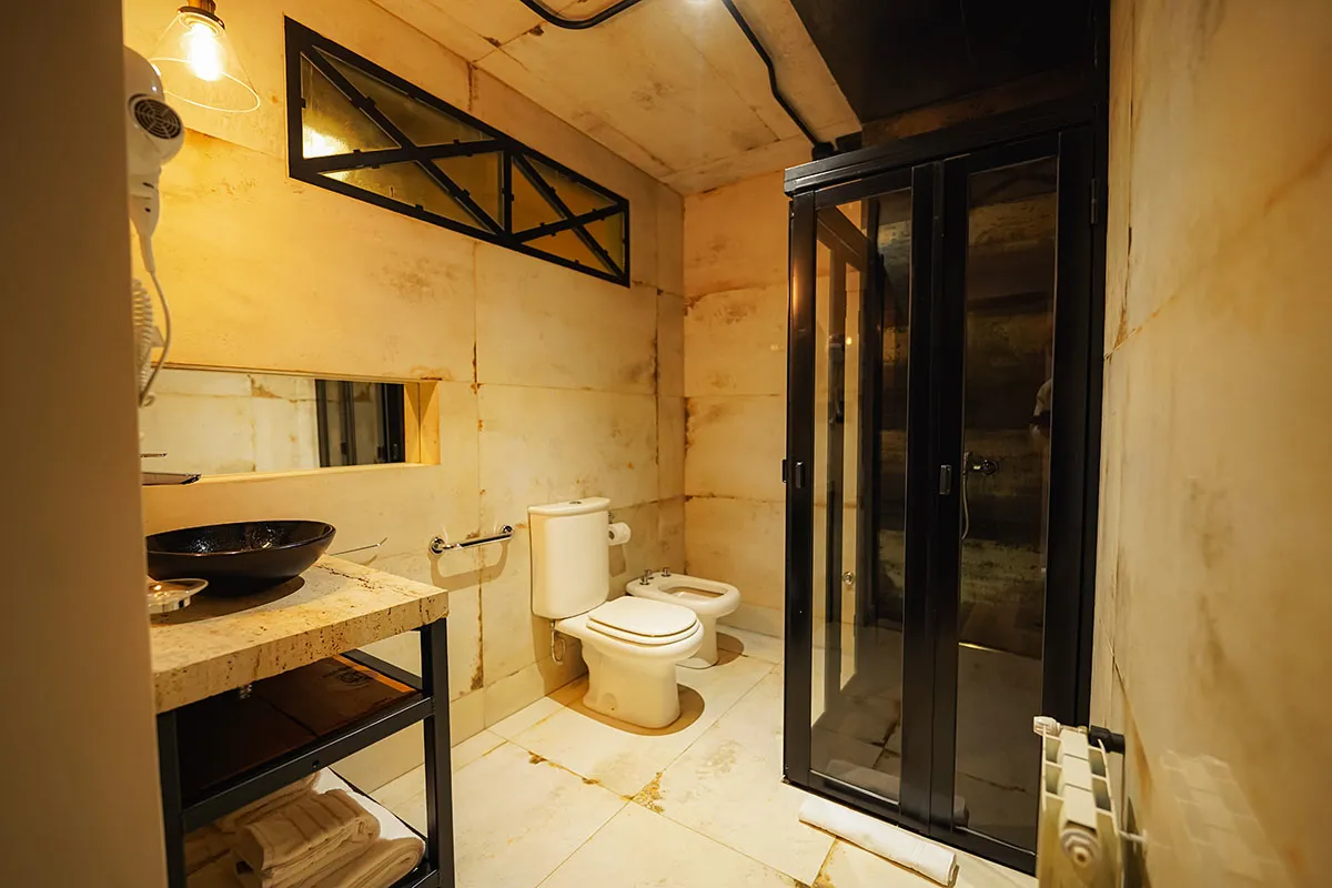 Baño con ducha de puertas plegables de vidrio, bidet y bacha negra